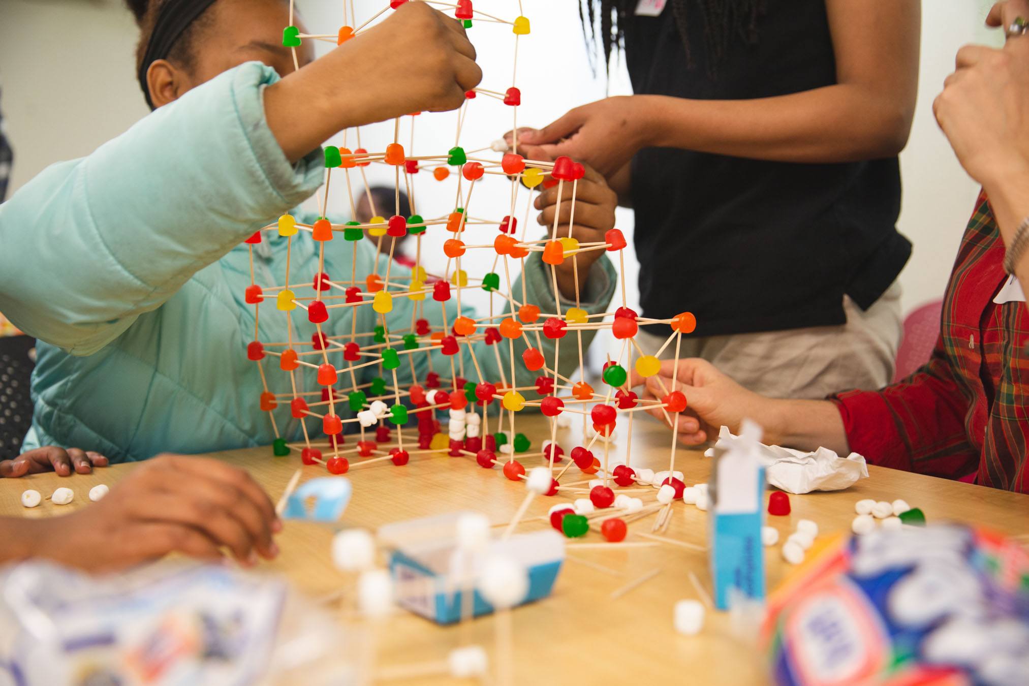 A student works on an architectural model using toothpicks and candy as part of a volunteer exercise