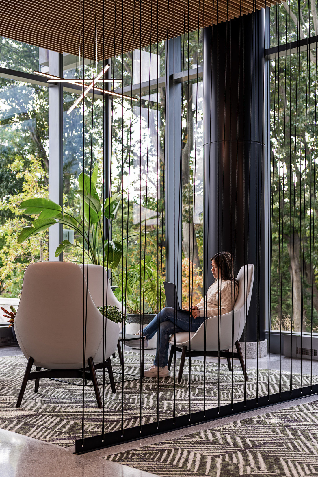 A woman sits in a lounge area with natural views at 100 Forge.