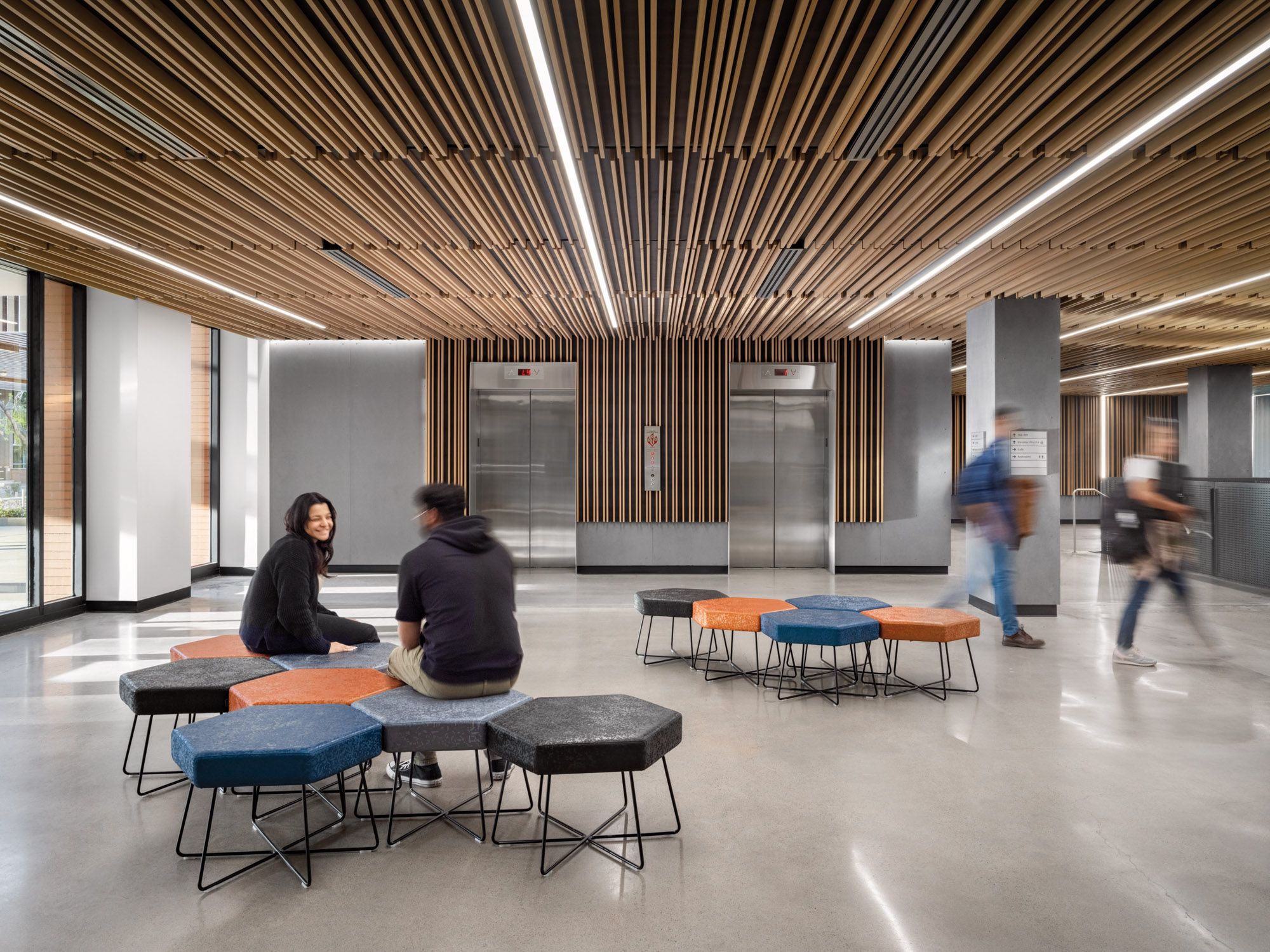 Students seat in hexagon-shaped seating in the first-floor elevator lobby at Durham Hall