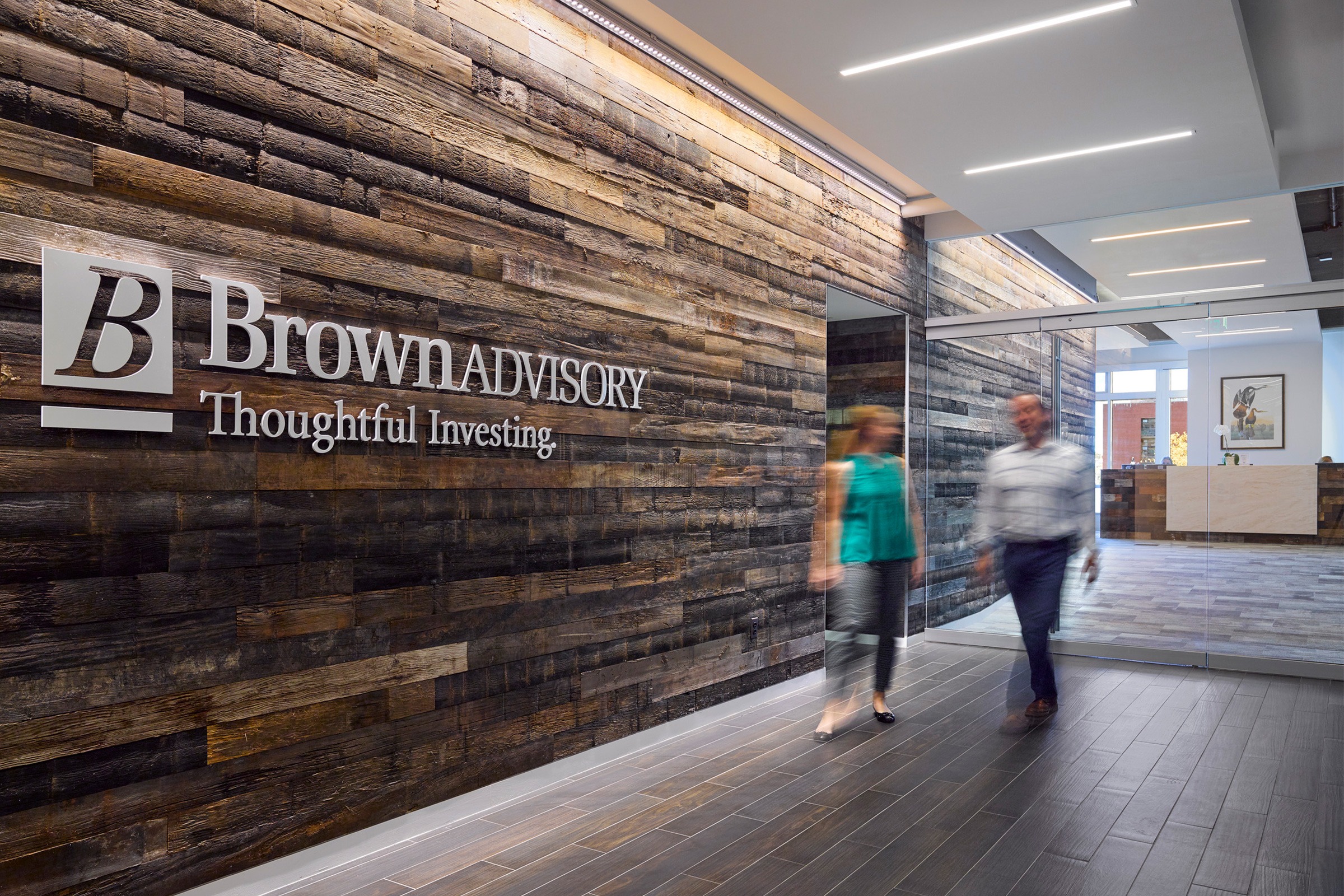 Lobby feature wall with wood detailing. Corporate logo and slogan read “Brown Advisory: Thoughtful...