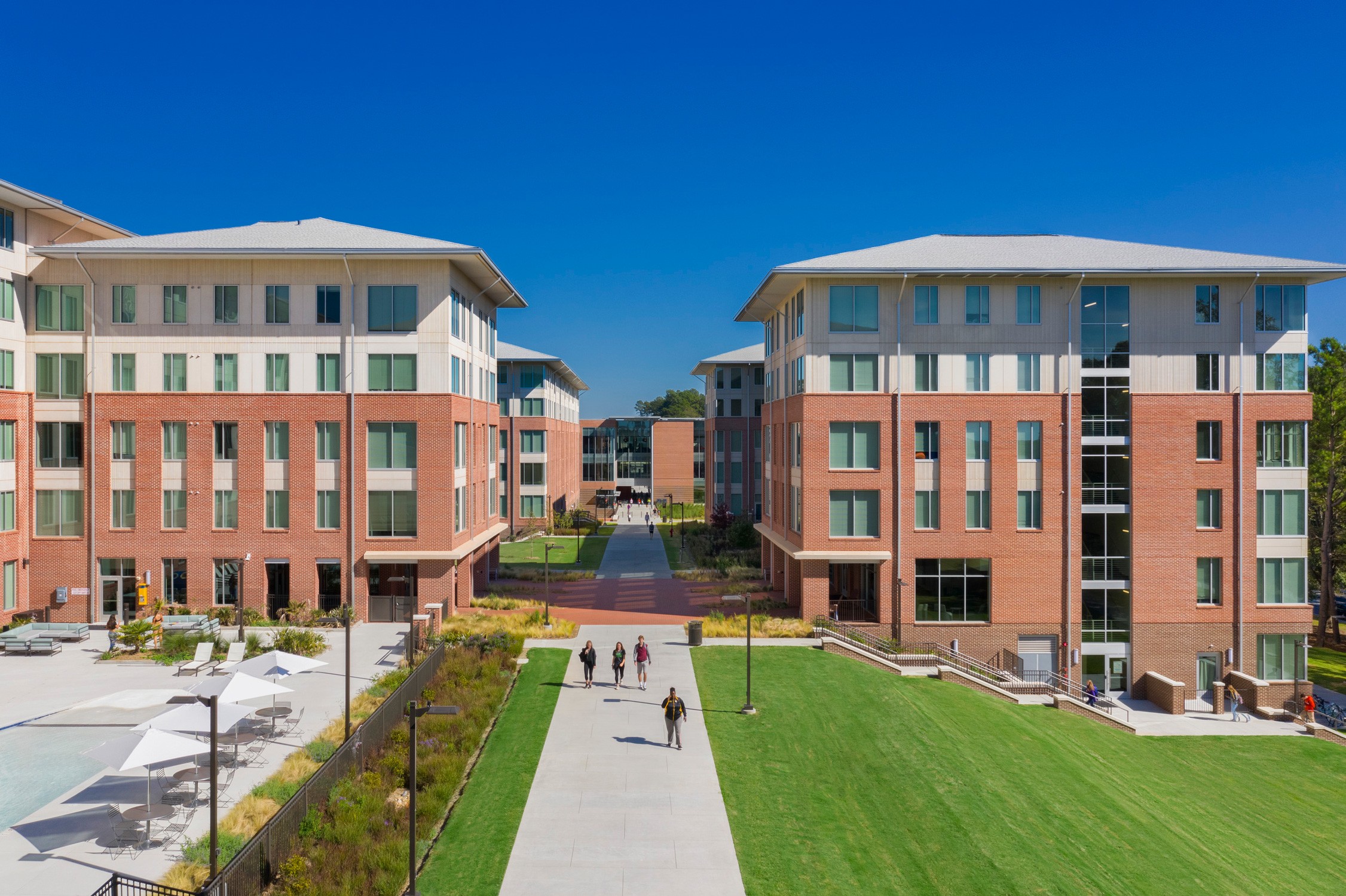 Exterior view of the residence halls on either side of a pedestrian path as part of the Douthit...