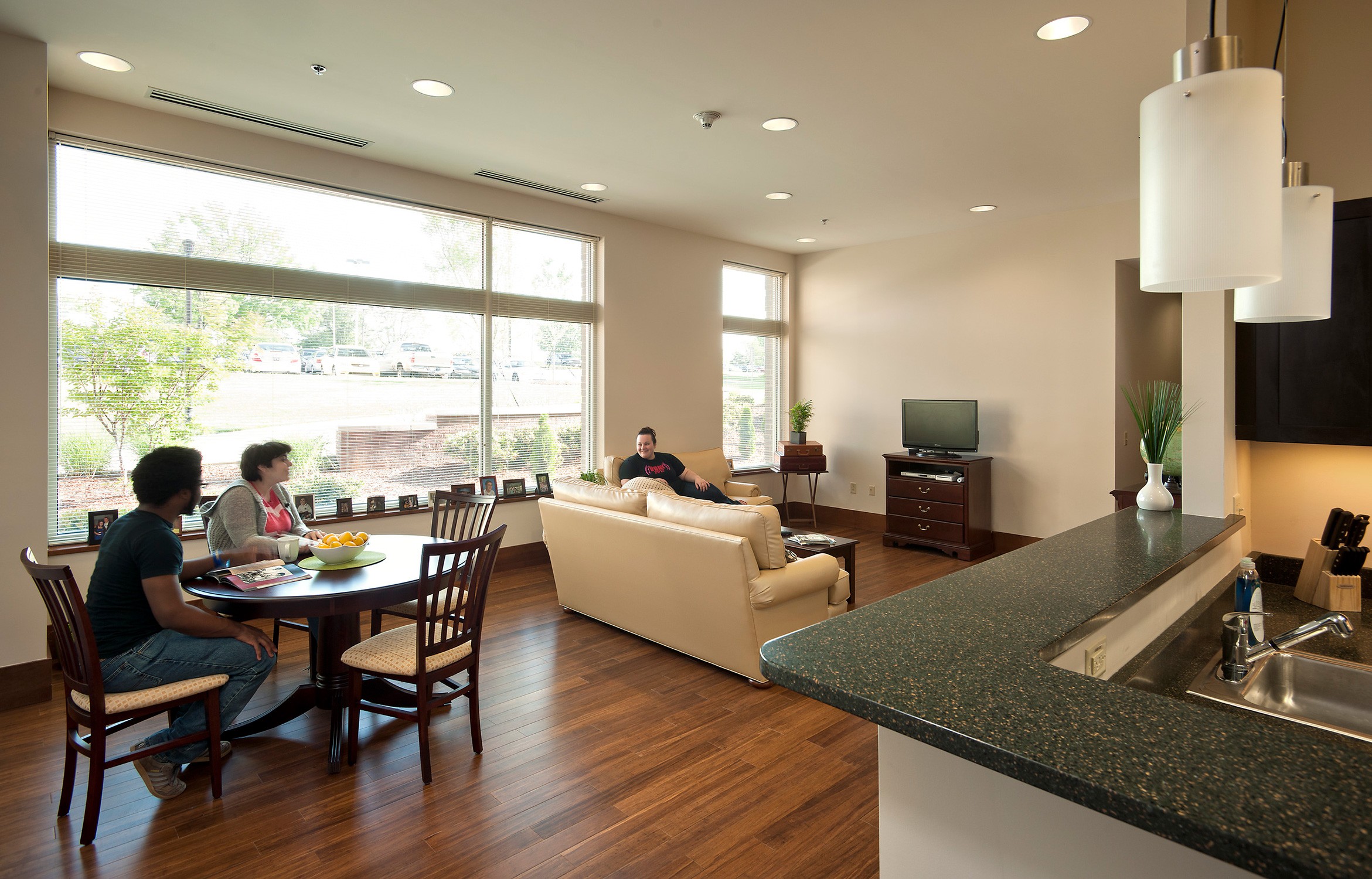 Interior view of residents socializing in dining and living space in an apartment unit at Jefferson...