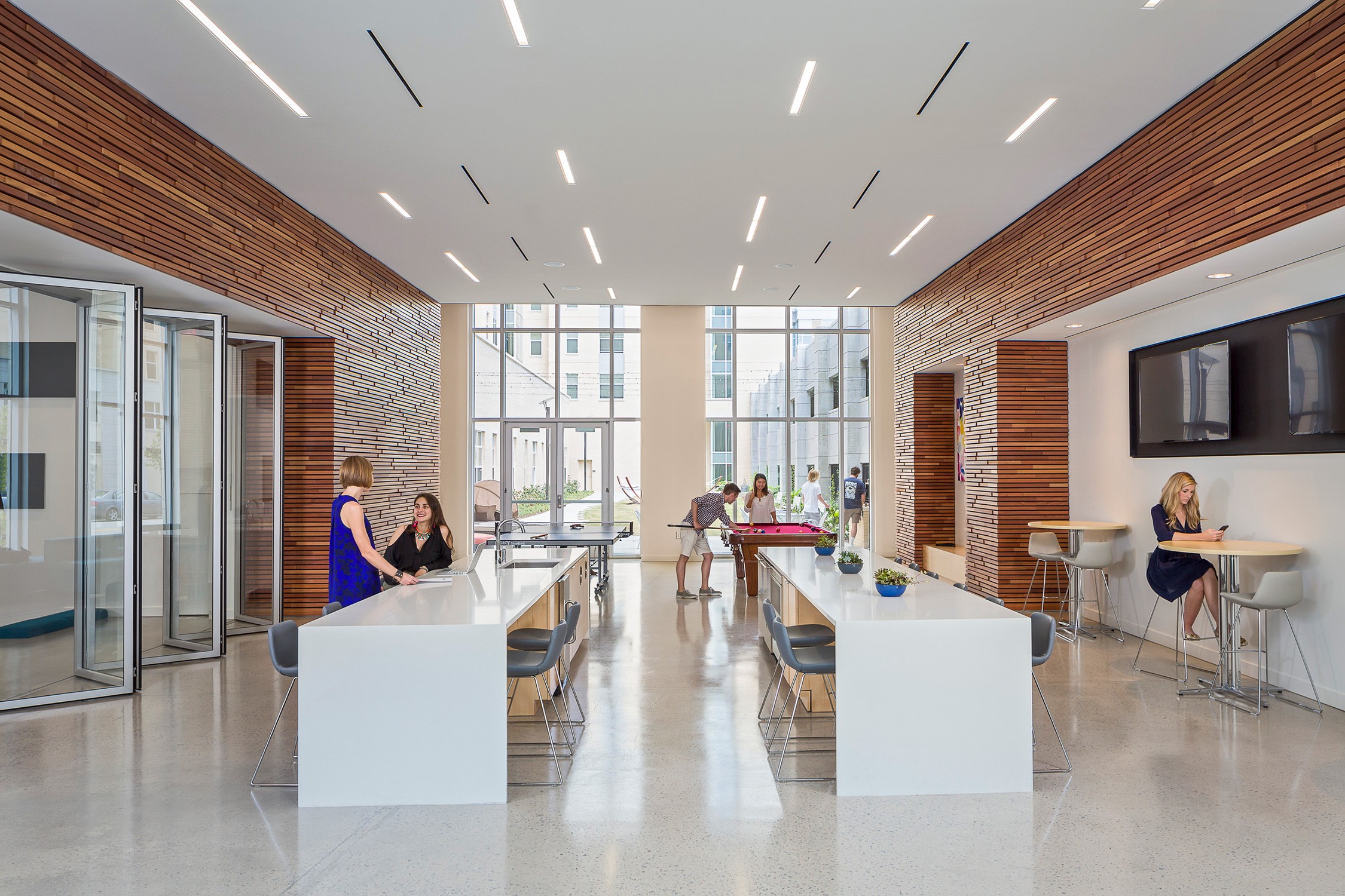 Interior view of residents conversing and recreating in a ground floor common space in 650 Lincoln...
