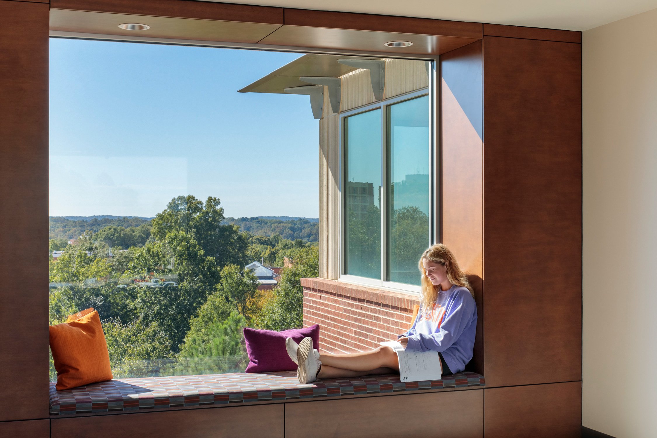 Interior view of a student studying on a window bench inside one of the residence halls at Douthit...