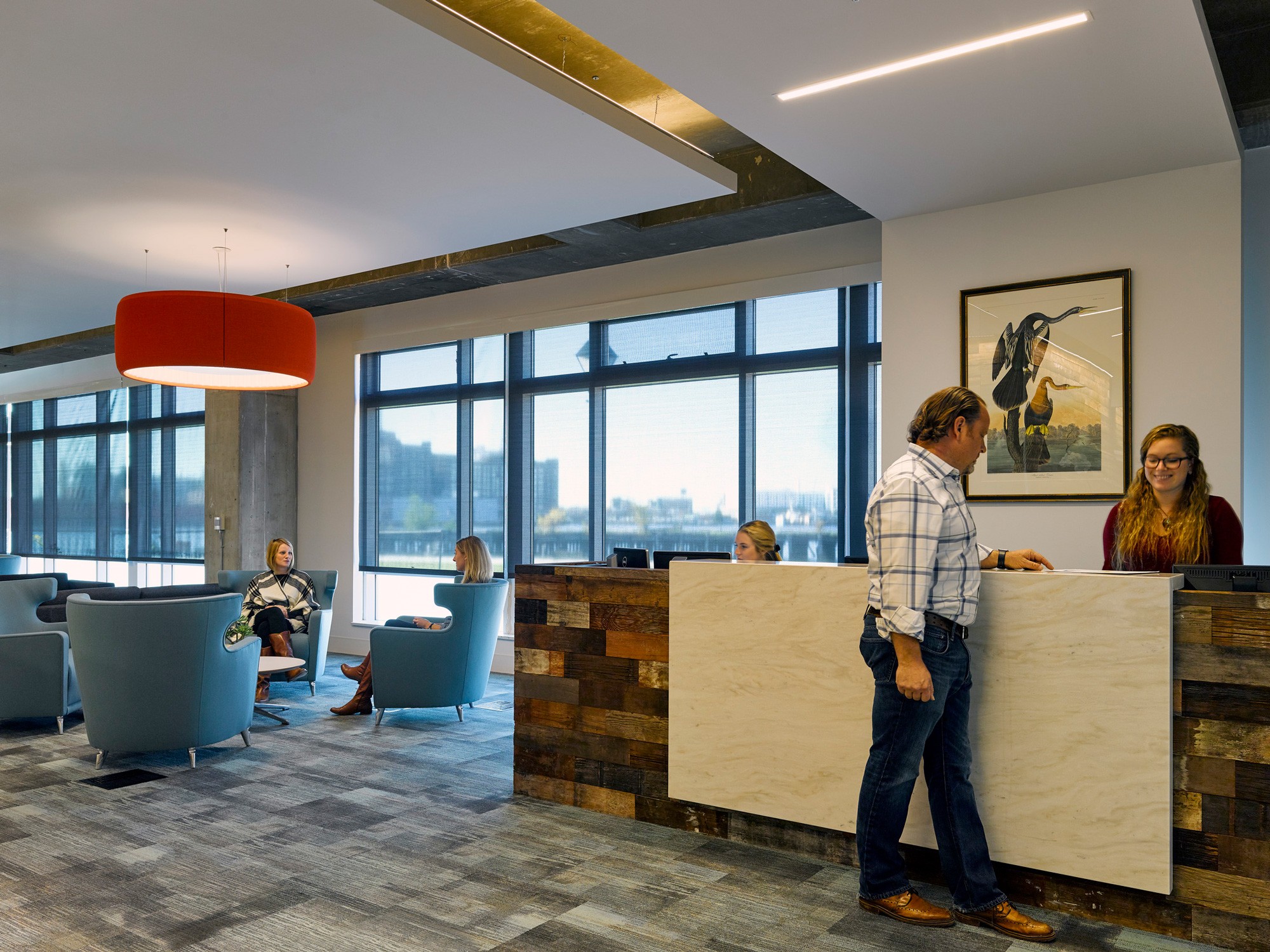 Brown Advisory lobby featuring front desk with wood detailing next to seating area with blue wingback...
