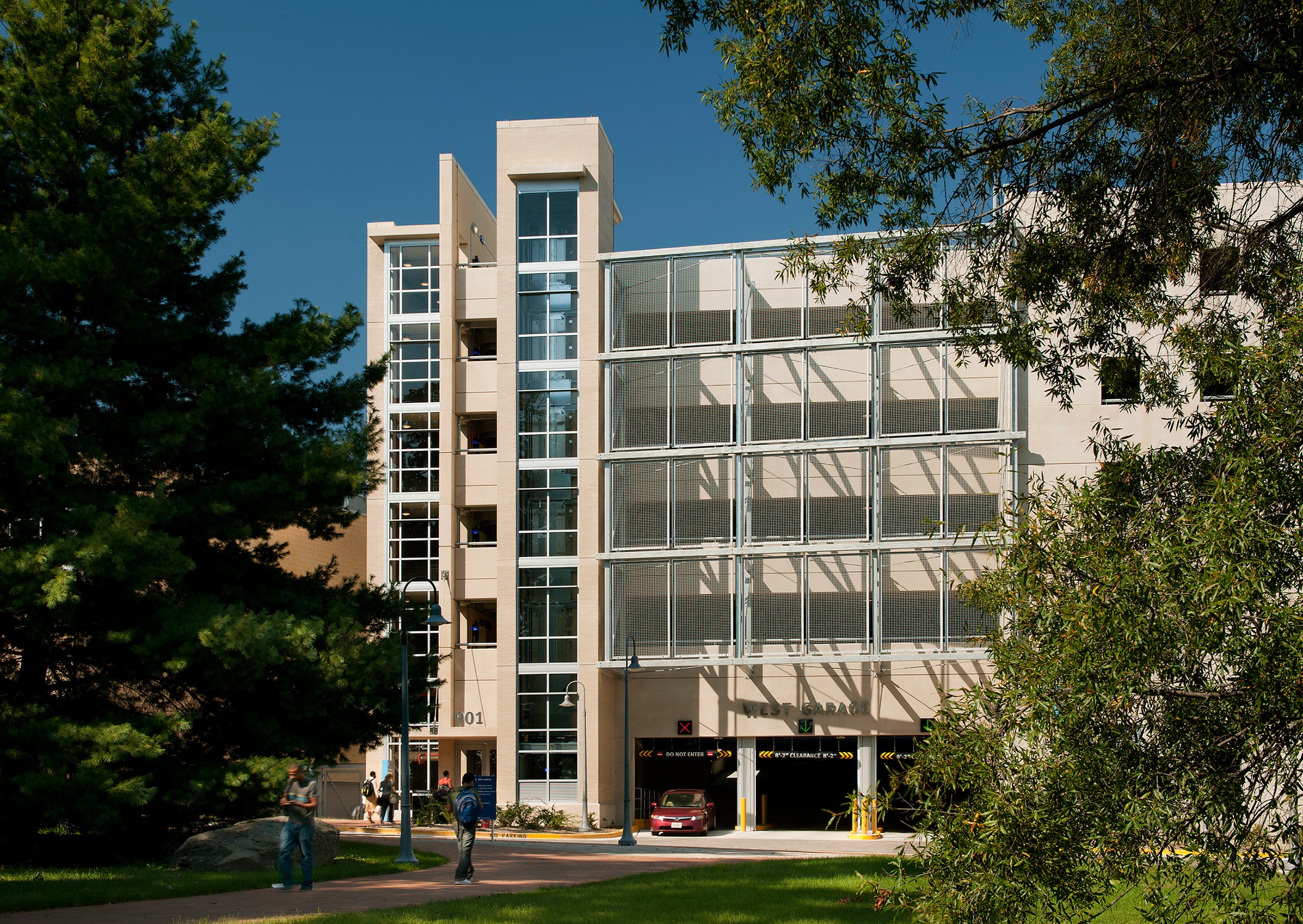 Front of the parking garage for Montgomery College and entrance with students and trees in the...