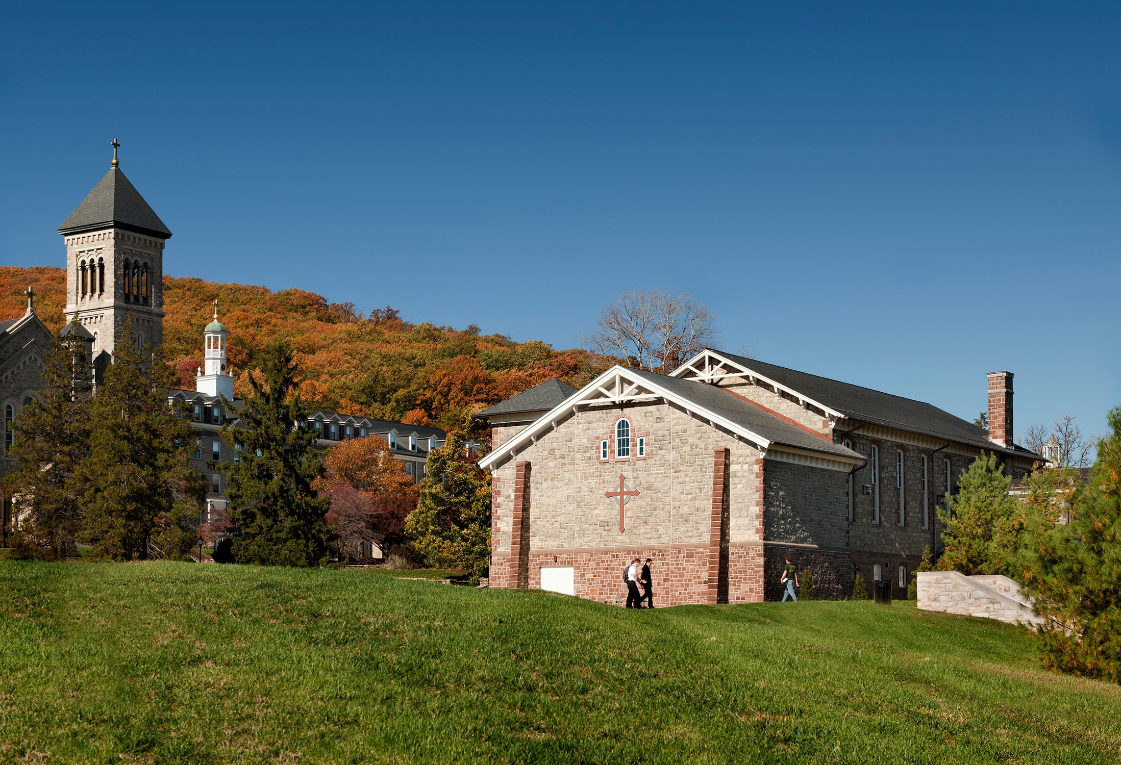 In context with the campus and fall leaves, featuring a cross on the stone façade Exterior of the...