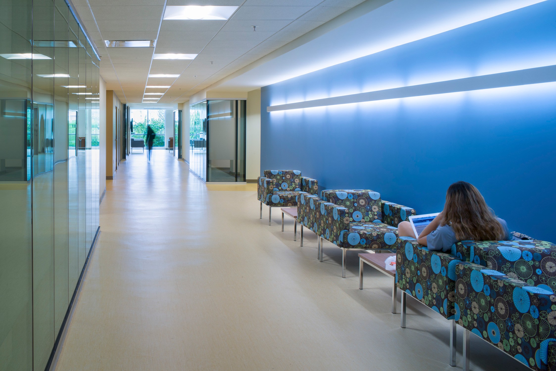 Renovated corridor featuring a bright blue wall with accent lighting and patterned furniture. A...