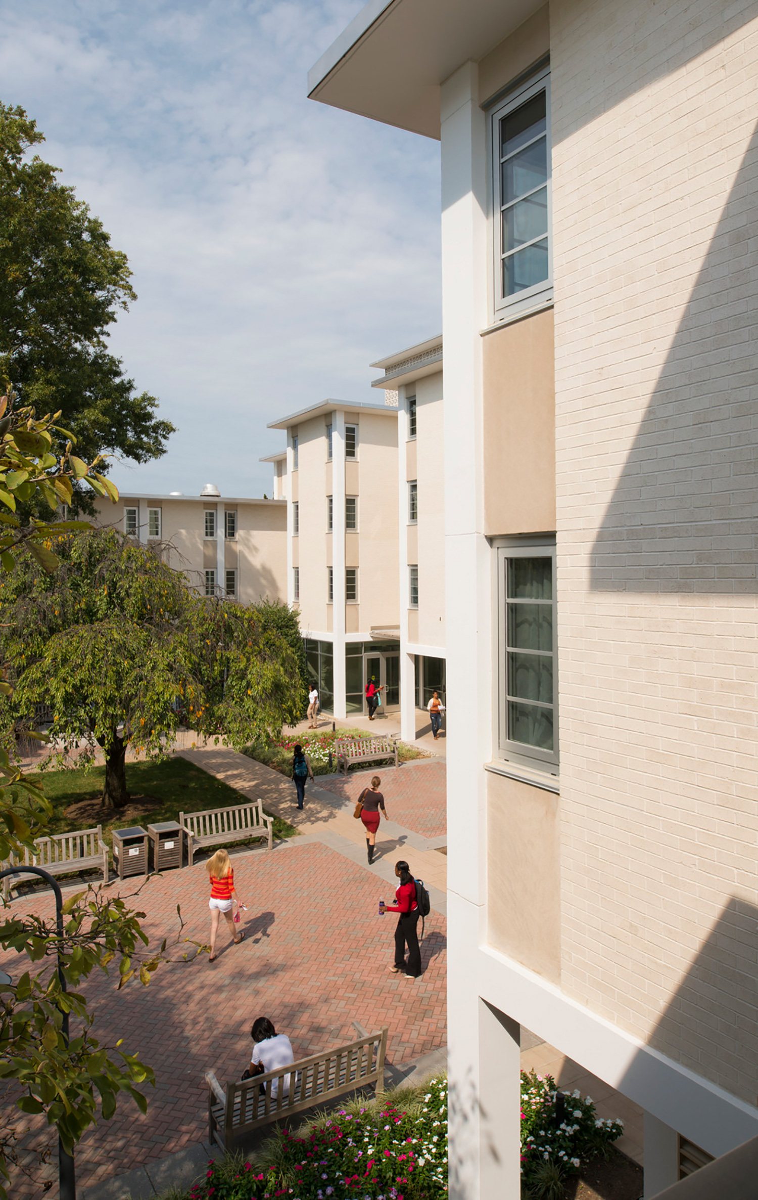 Rowley Hall exterior with white walls looking onto tree and plant lined brick courtyard.
