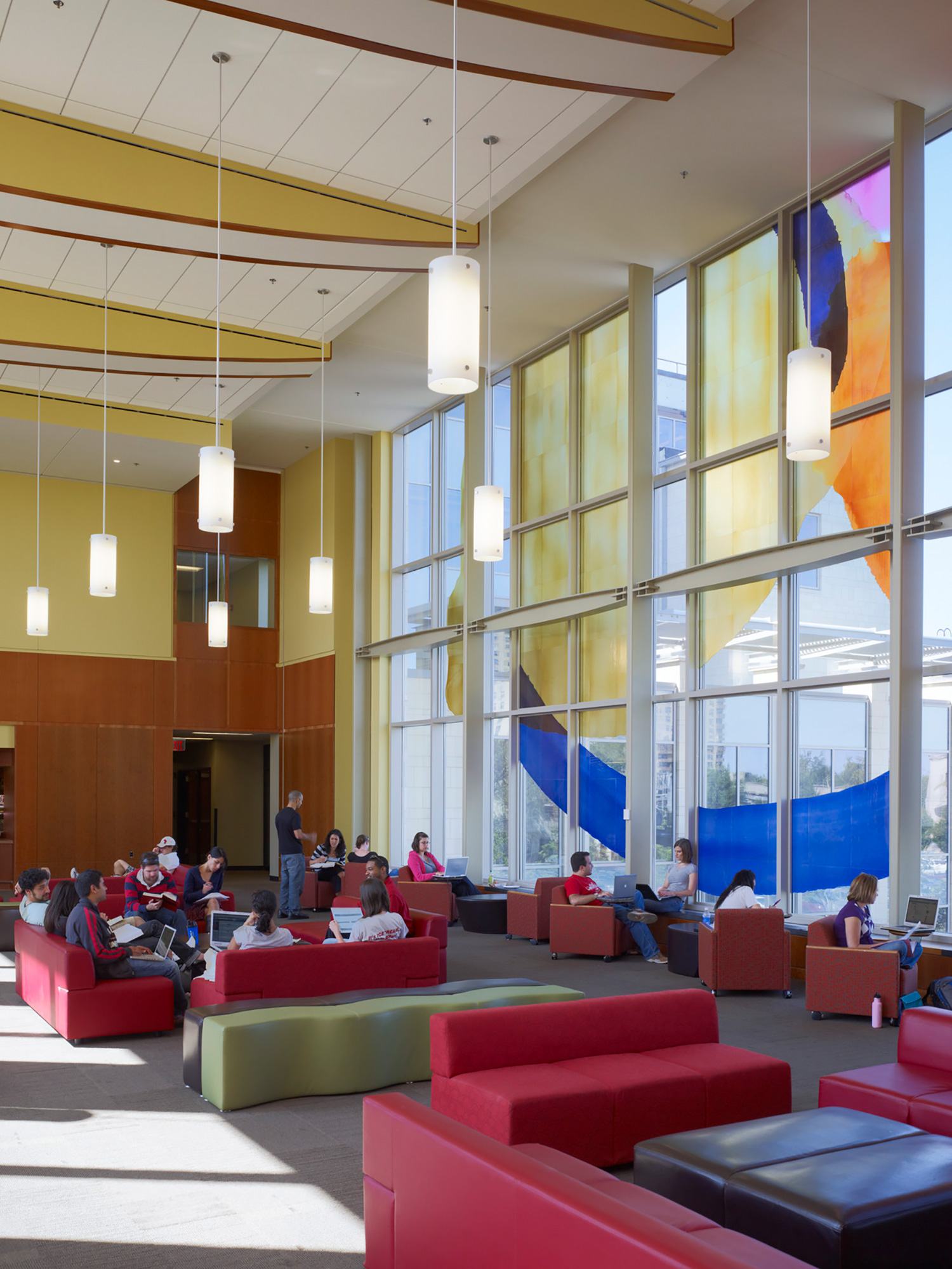 Students study together in a colorful lounge with bright red furniture and colorful paint on the...