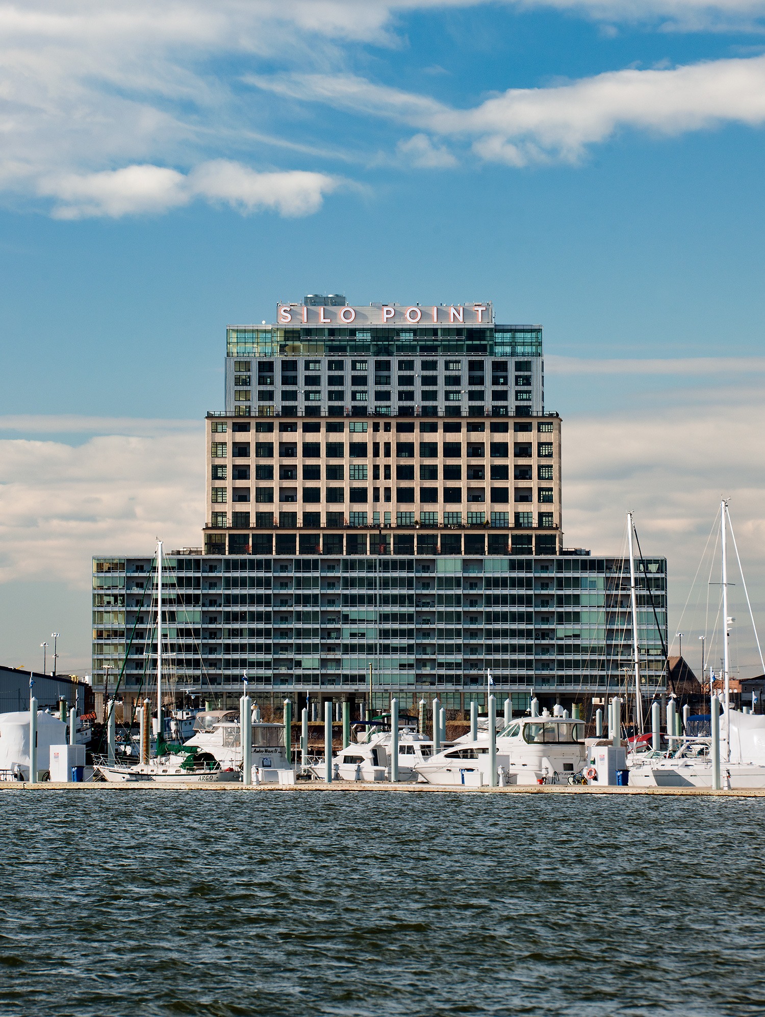 White and orange sign letters at the top of Silo Point from the harbor