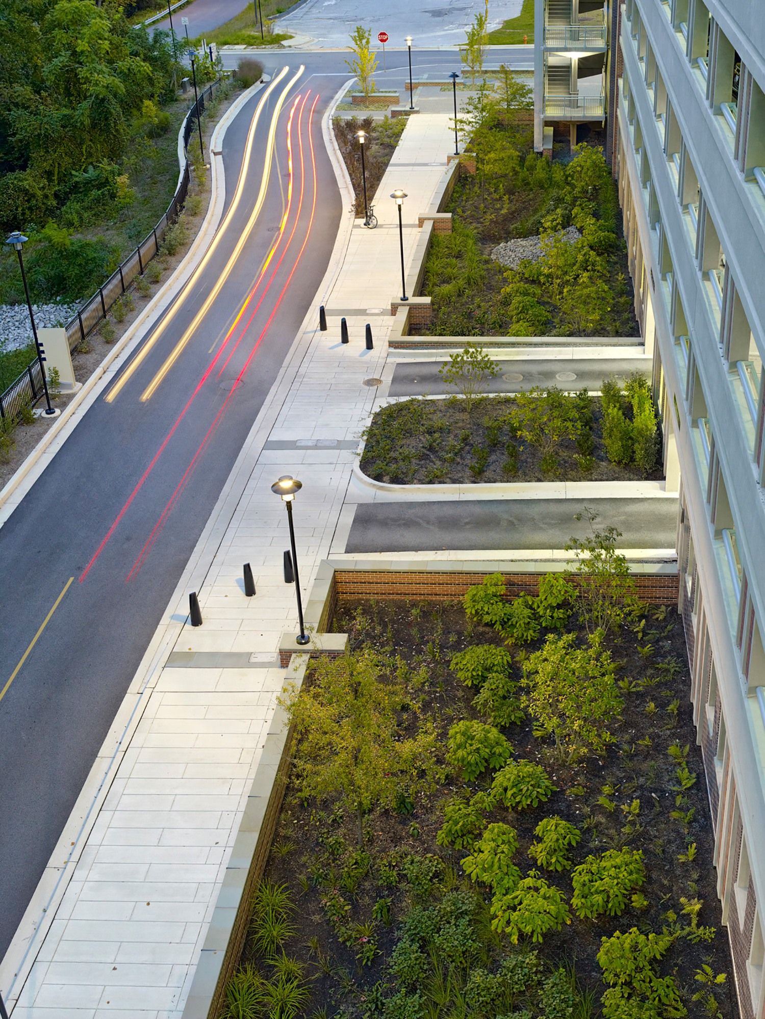 Landscaped stormwater retention area with trees and plantings adjacent to the parking garage at...