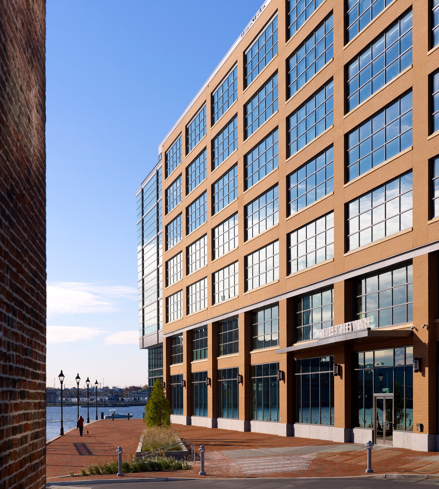 Entrance to the Thames Street Wharf building on a brick promenade with the Inner Harbor in the...