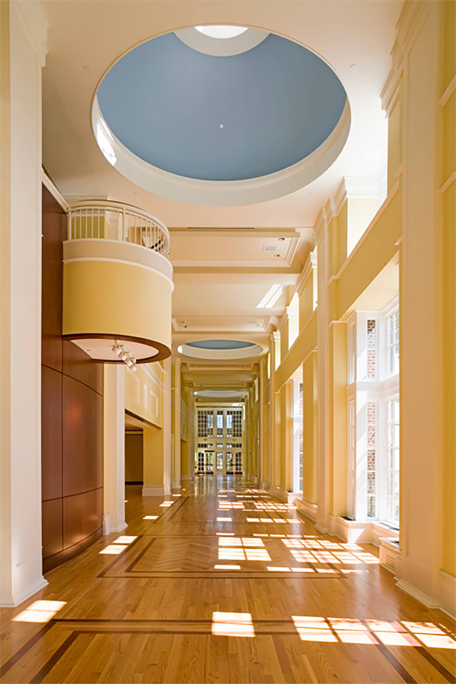 Lobby of performance space with light wood floors and dark wood inlay, wood wall paneling, and...