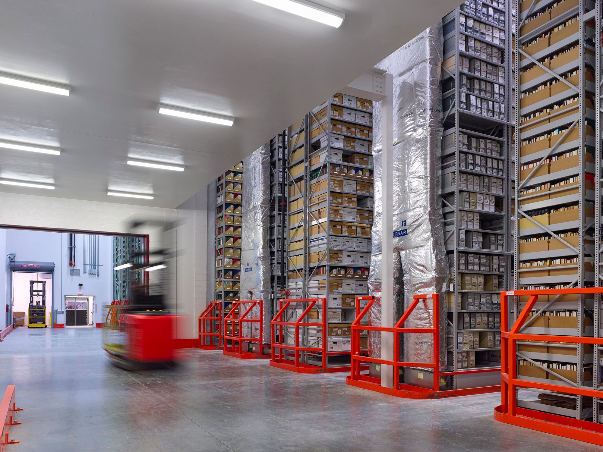 View into adjacent storage bay with forklift moving storage units at Washington Research Library...