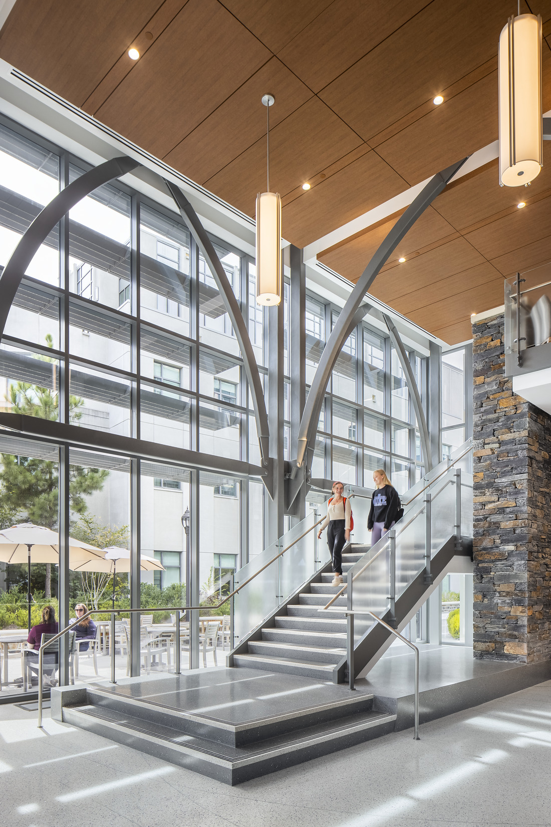 Students walk down the central stair in the Duke Health Center for Interprofessional Education...