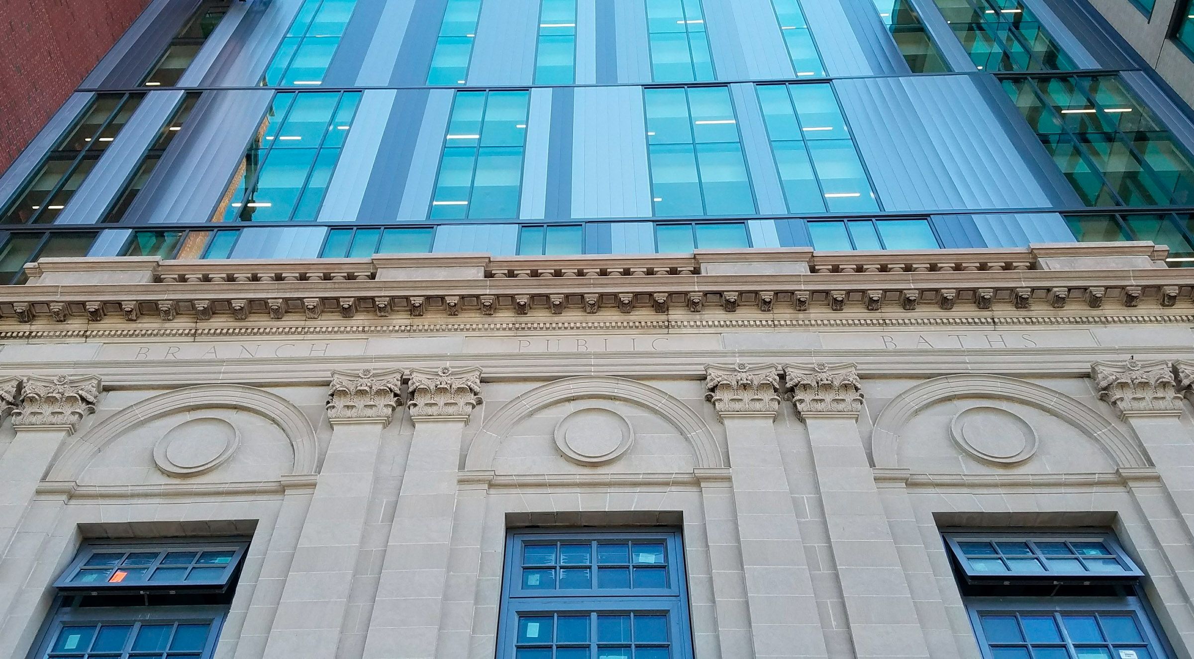Image from the ground looking up at the historic bath house and the new façade of the Gladding...