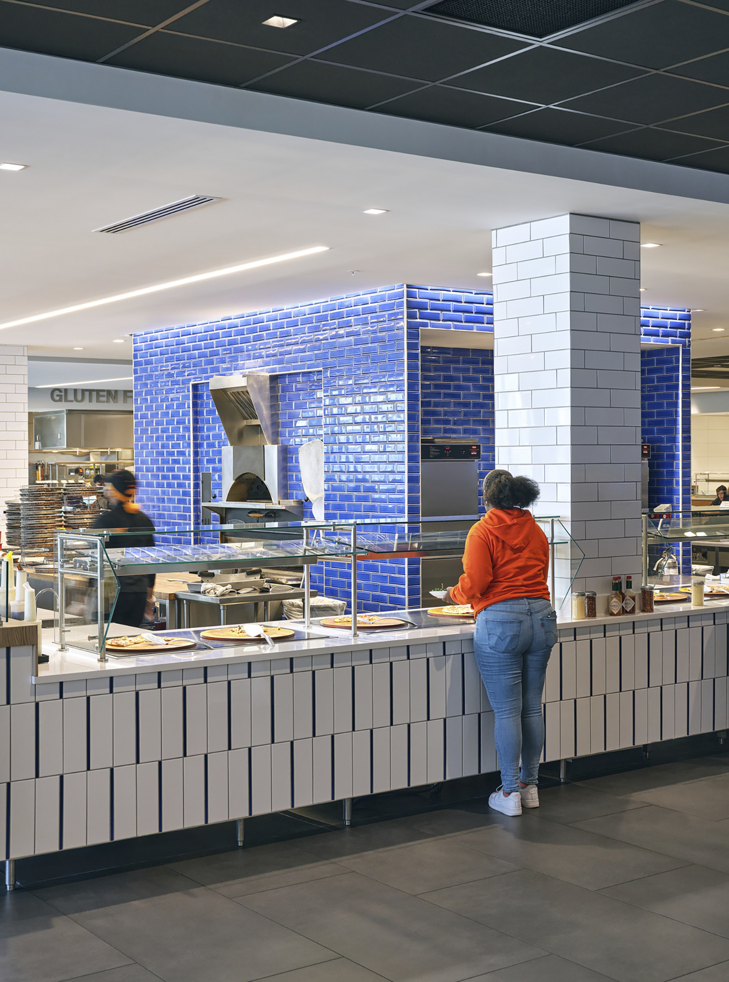 A student waits for food at the Mediterranean food station, which features a pizza over surrounded...