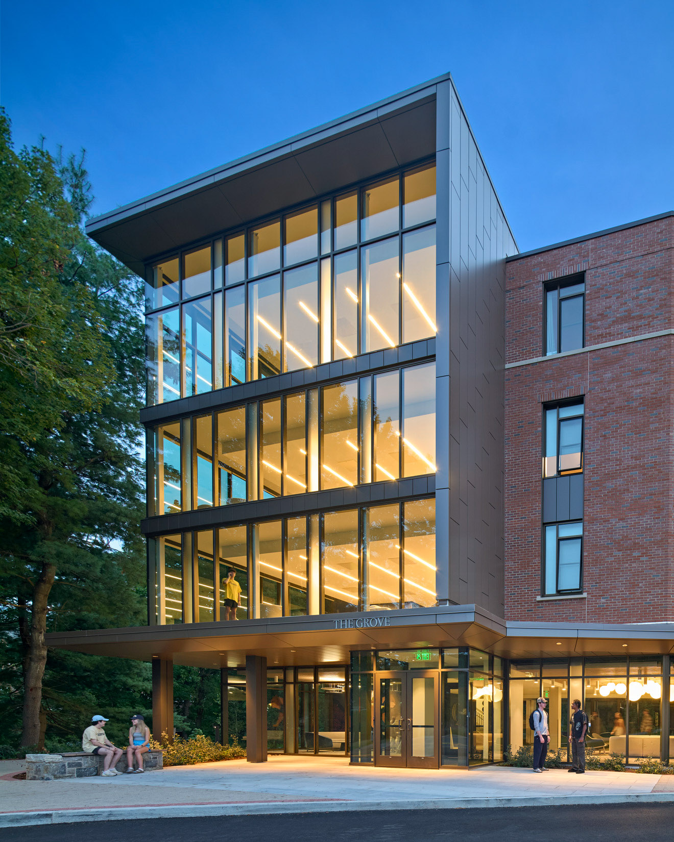 An evening view looking in at common student areas at Quinnipiac University's The Grove