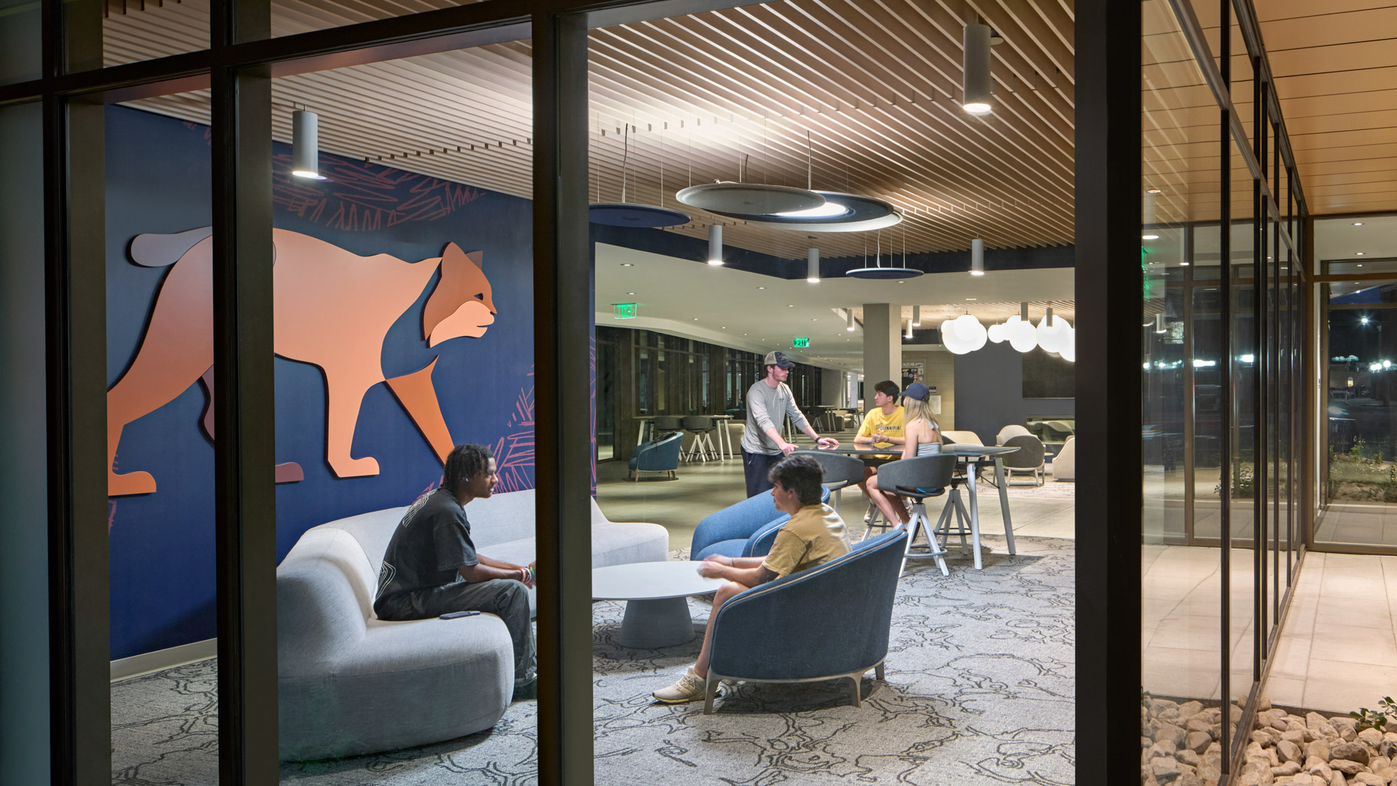 An evening view looking in at common student areas at Quinnipiac University's The Grove