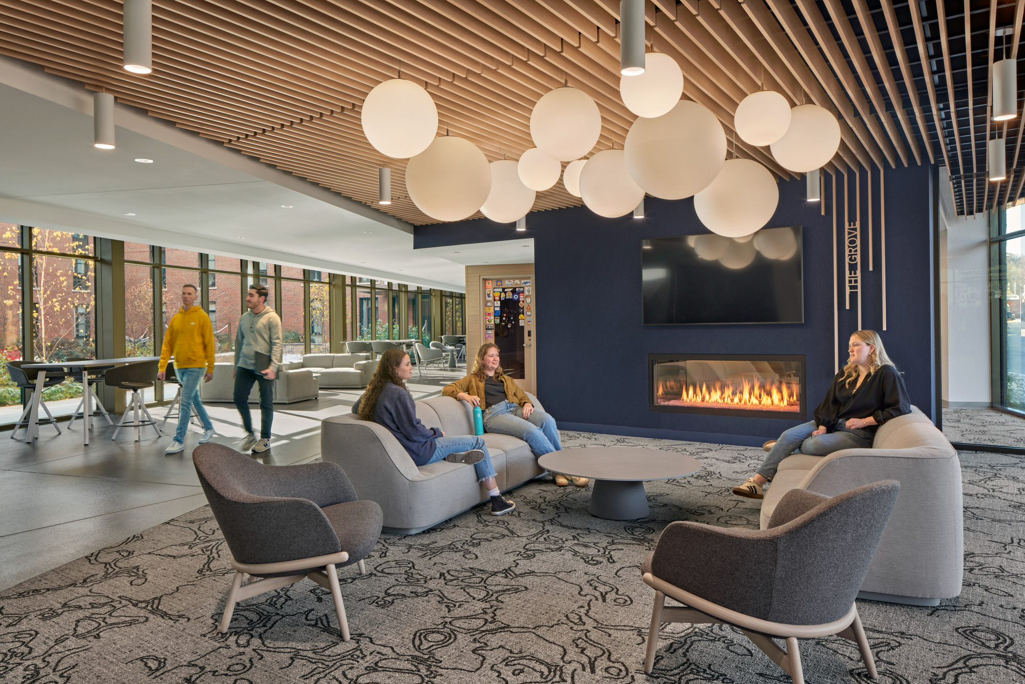 A student gathering space in The Grove features a statement lighting piece and fireplace.