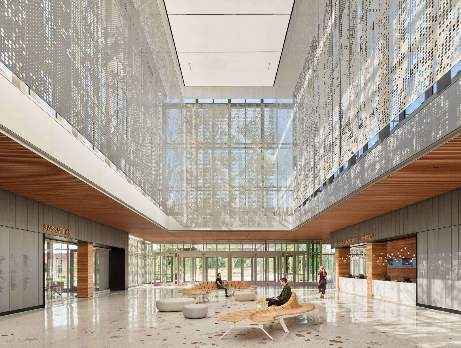 An interior view of the Missouri Botanical Garden Jack C. Taylor Visitor Center featuring people sitting on benches and a lantern inspired by a tree canopy. 