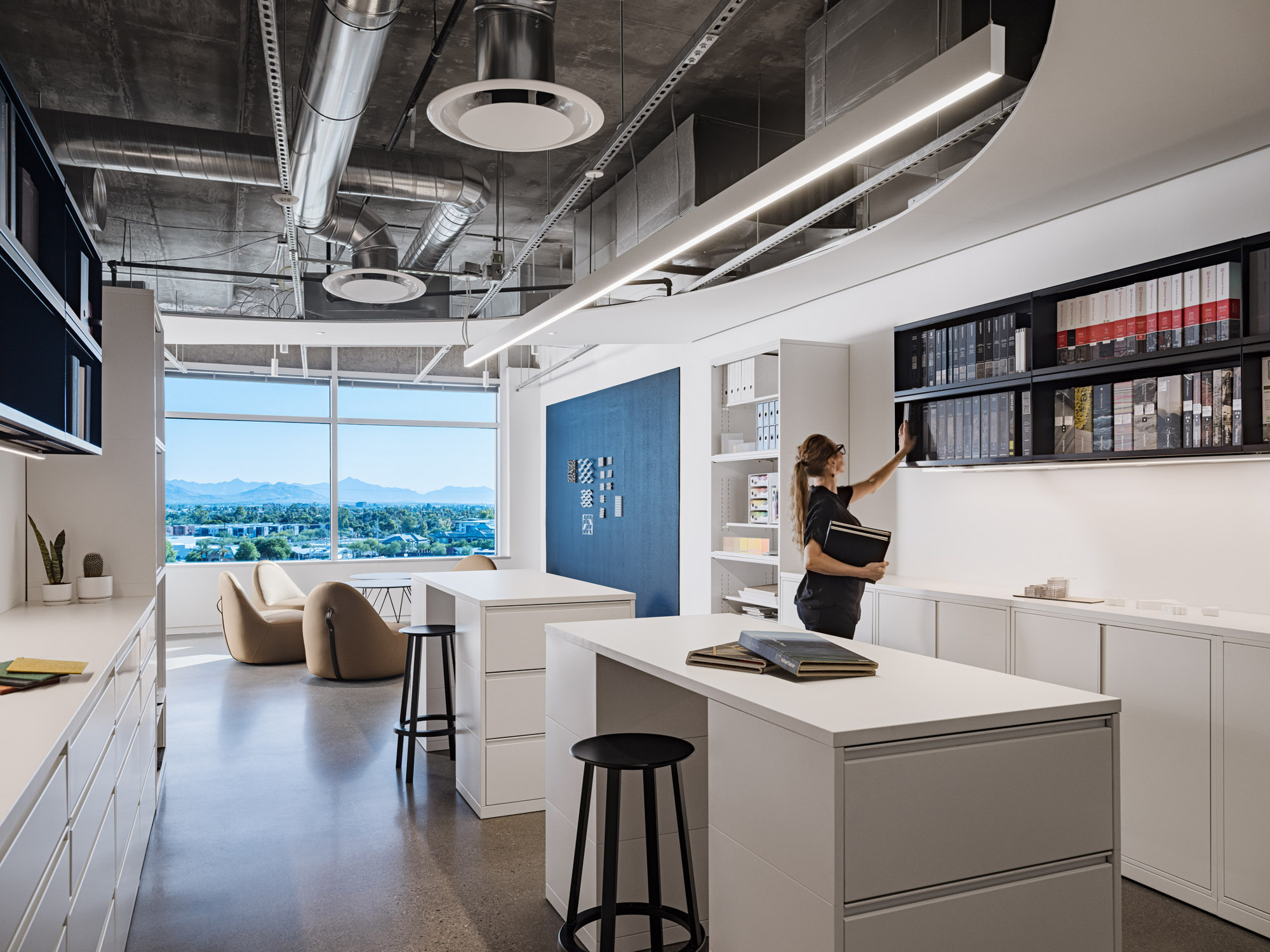 A woman looks for a book on a shelf of a modernly designed office.