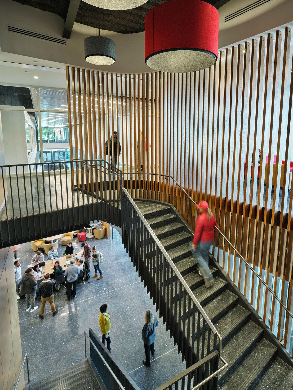 Open stair with wood slat screen overlooks an active student commons below.