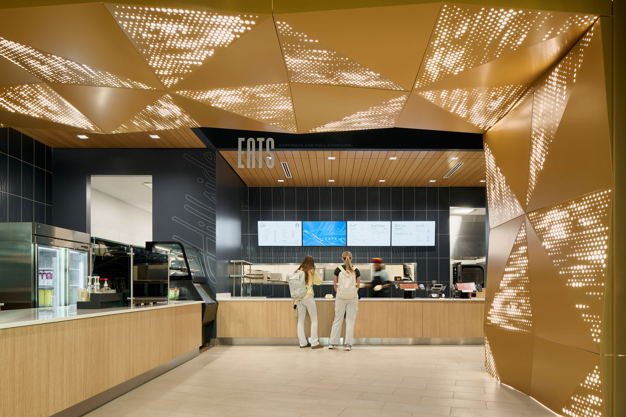 Interior view of the nursing building café with a service counter, digital menu boards, warm wood...
