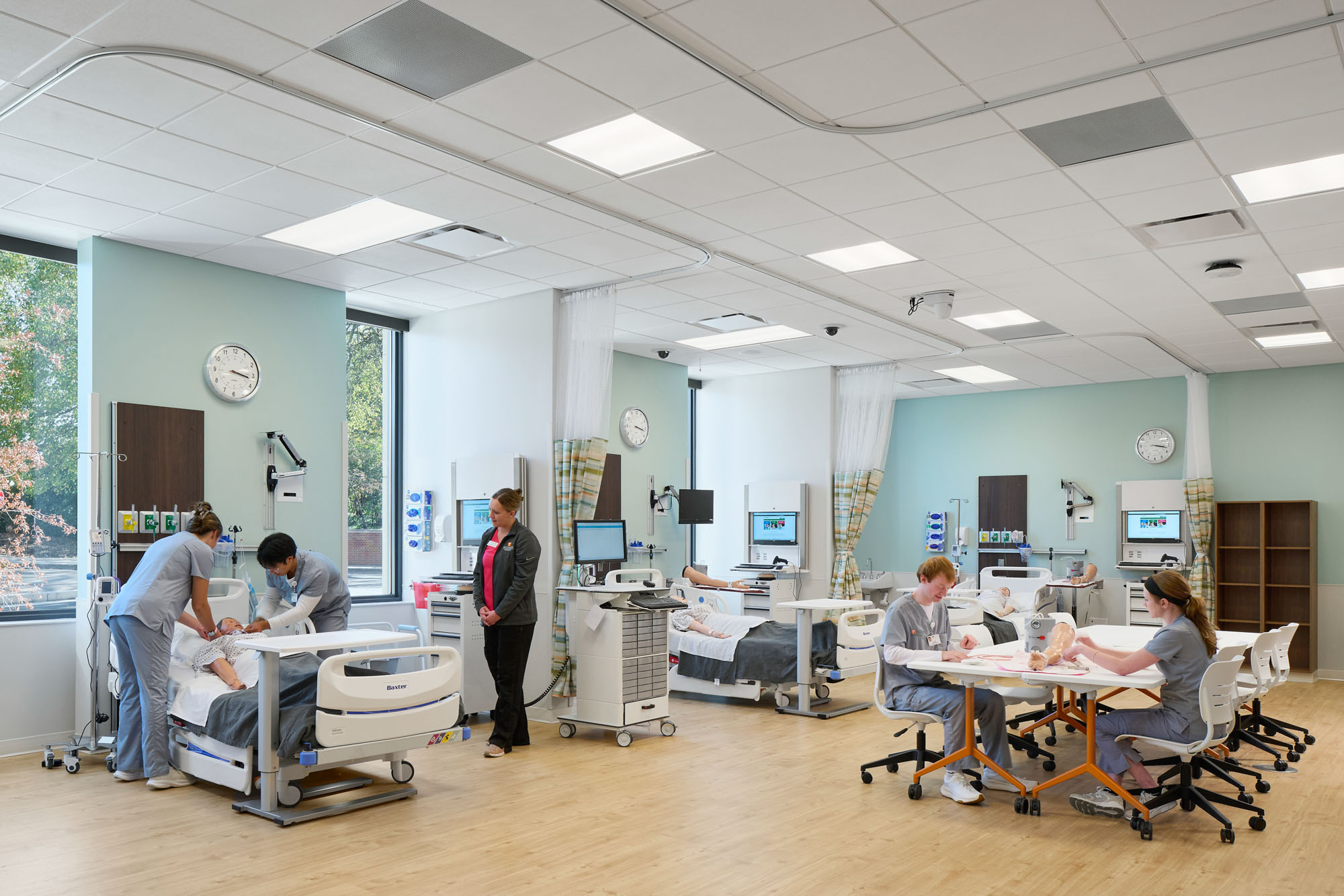 Nursing simulation lab with hospital beds, medical equipment, and students practicing patient care...