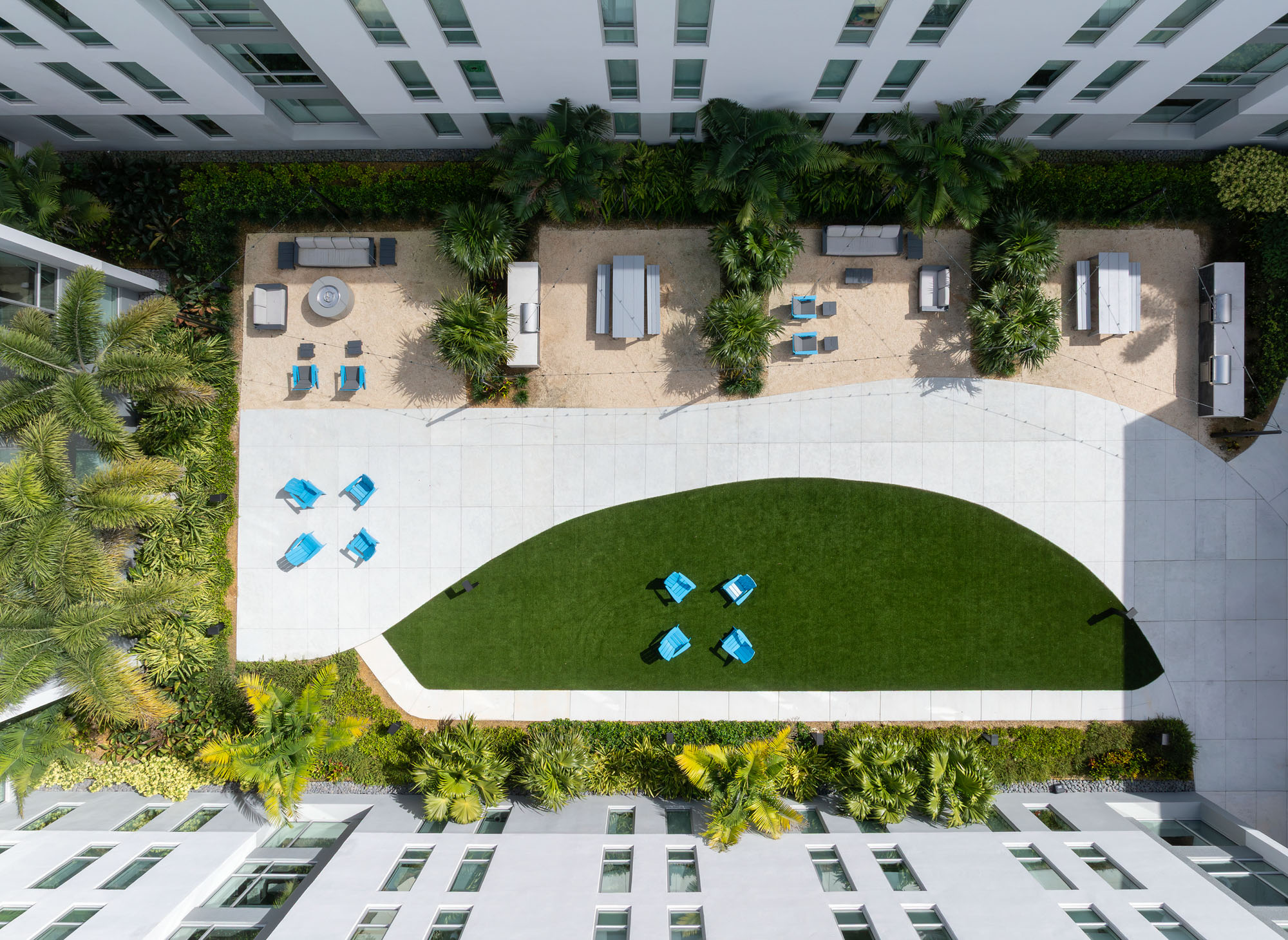 Overhead daytime view of the Banyan Residence Hall courtyard. A curved turf lawn occupies the lower...